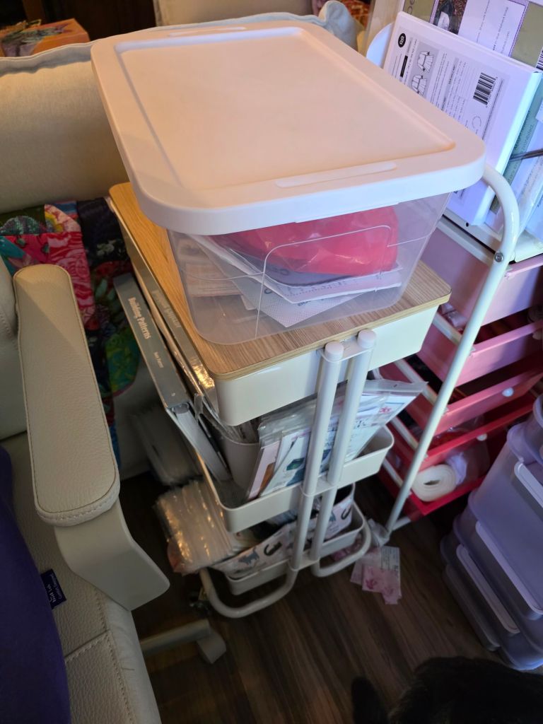 A compact storage cart with a wooden top and multiple layers of bins and file organizers, surrounded by a home setting.